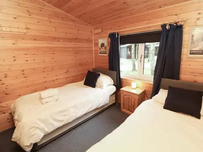 two beds in a room with wooden walls at The Fold in Keswick