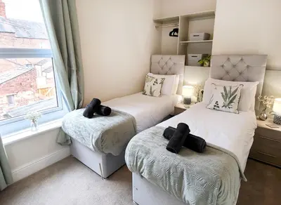 two twin beds in a room with a window at Douglas House, near Hospital, attractive and comfy 2 bedroom House with enclosed yard to rear in Carlisle