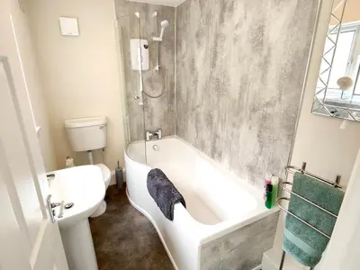 a bathroom with a white tub and a toilet at Douglas House, near Hospital, attractive and comfy 2 bedroom House with enclosed yard to rear in Carlisle