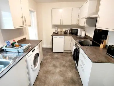 a kitchen with white cabinets and a washer and dryer at Douglas House, near Hospital, attractive and comfy 2 bedroom House with enclosed yard to rear in Carlisle