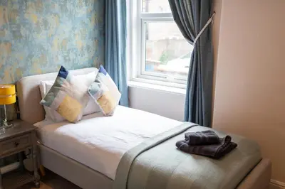 a small bed in a room with a window at Russell House, Large townhouse spacious and modern with ground floor bedroom and shower room and free parking in Harraby