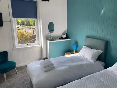 a bedroom with a bed and a chair and a window at Queensberry arms hotel in Kirkconnel