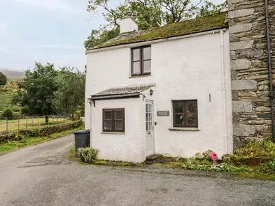 a white house with a window and a street at Beckfold Cottage in Broughton in Furness