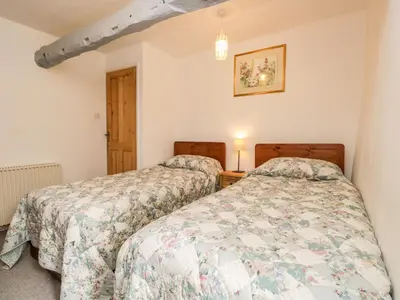 two twin beds in a room with two lamps at Beckfold Cottage in Broughton in Furness