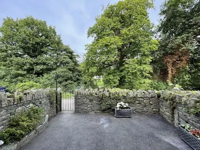 a stone fence with a stone gate and a suitcase at Fairbank in Keswick