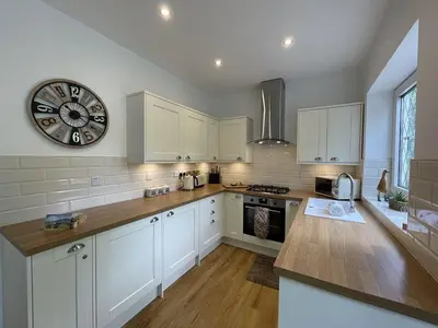 a kitchen with white cabinets and a clock on the wall at Fairbank in Keswick