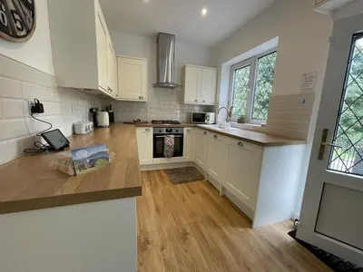 a kitchen with white cabinets and a wooden floor at Fairbank in Keswick