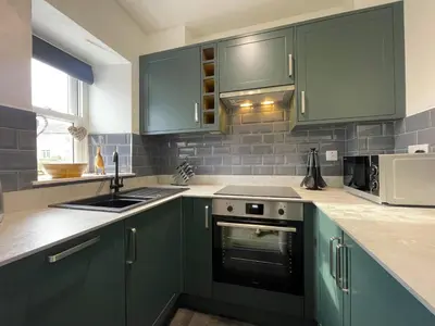 a kitchen with green cabinets and a sink at Gretaside in Keswick