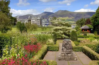 a garden in front of a large house with mountains in the background at Gretaside in Keswick