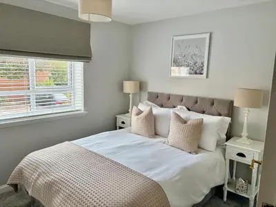 a bedroom with a bed with white sheets and pillows at Kinfirth Apartment in Ayr
