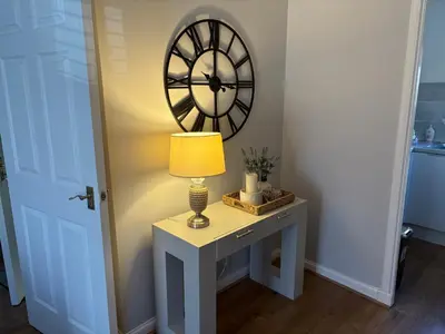a table with a lamp and a clock on the wall at Kinfirth Apartment in Ayr