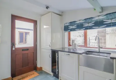 a kitchen with a sink and a window and a door at Camerton Hall Cottage in Workington