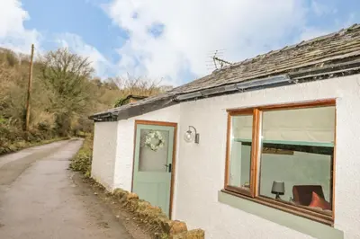 a white cottage with a window and a road at Camerton Hall Cottage in Workington