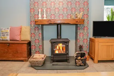 a fireplace in a living room with a stove at Camerton Hall Cottage in Workington