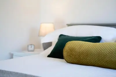 a bed with green and white pillows and a lamp at Grasmere Cottage with Stunnng Views by LetMeStay in Ambleside
