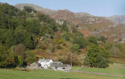 a house in a field in front of a mountain at Grasmere Cottage with Stunnng Views by LetMeStay in Ambleside