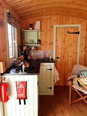 a kitchen in a log cabin with a sink at Fauld O Wheat Shepherds Hut , Loch Ken ,Off Grid in Castle Douglas