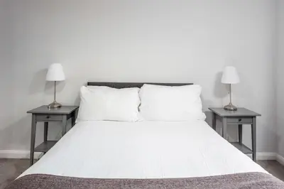 a white bed with two nightstands and two lamps at Prestwick Central - Donnini Apartments in Prestwick