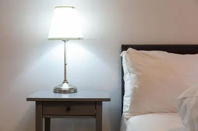 a lamp on a night stand next to a bed at Prestwick Central - Donnini Apartments in Prestwick
