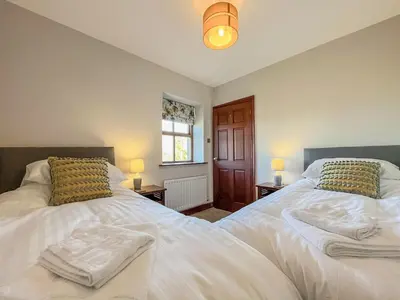 a bedroom with two beds and two lamps and a window at Ellerton Croft in Wreay