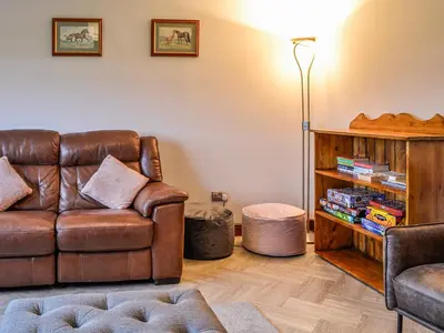 a living room with a leather couch and a book shelf at Ellerton Croft in Wreay