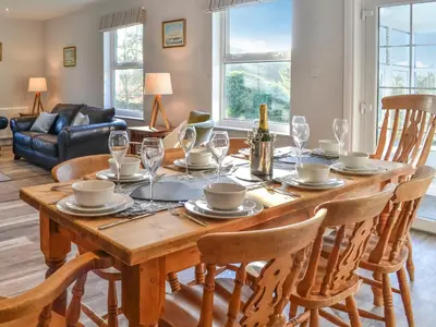 a dining room table with chairs and a bottle of champagne at Clarksburn Blue in Monreith