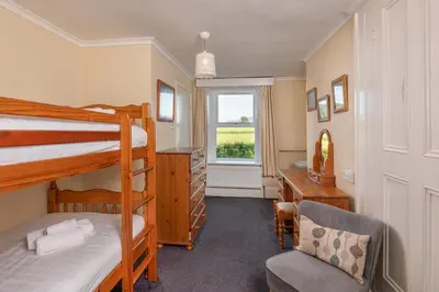 a bedroom with bunk beds and a desk and a chair at Big Pink House in Mealsgate