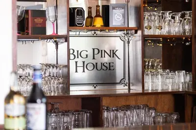 a big pink house sign in a bar with glasses at Big Pink House in Mealsgate