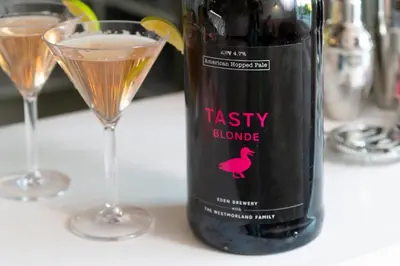 a bottle of wine on a table with two glasses at Big Pink House in Mealsgate