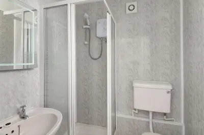 a bathroom with a shower and a toilet and a sink at Big Pink House in Mealsgate
