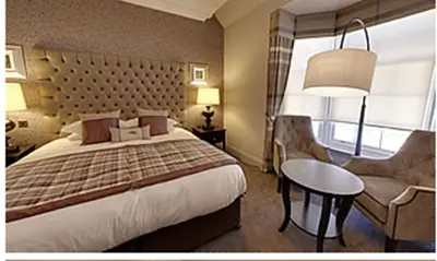 a hotel room with a bed and a table and a chair at Dumfries Arms Hotel in Cumnock