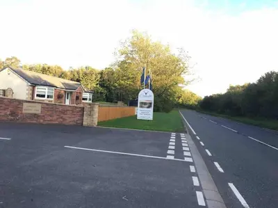 a road with a sign in front of a house at Woodpecker lodge, Camelot Holiday Park, CA6 5SZ in Carlisle