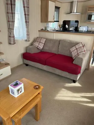 a living room with a red couch and a table at Woodpecker lodge, Camelot Holiday Park, CA6 5SZ in Carlisle