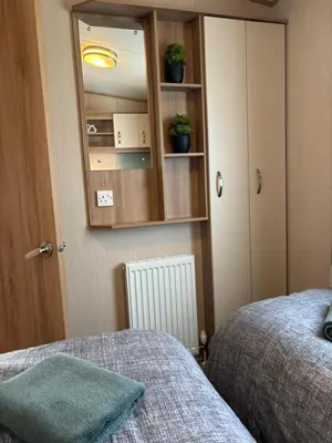 a bedroom with a bed and a cabinet with plants on it at Woodpecker lodge, Camelot Holiday Park, CA6 5SZ in Carlisle
