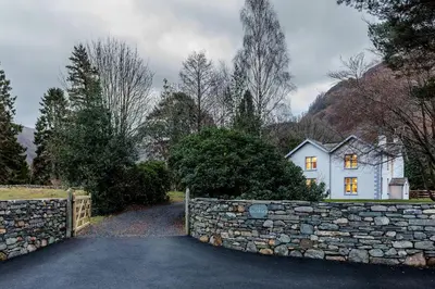a stone wall in front of a white house at The Vicarage in Keswick