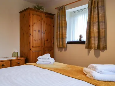 a bedroom with a bed and a window and towels at Scalelands Cottage in Frizington
