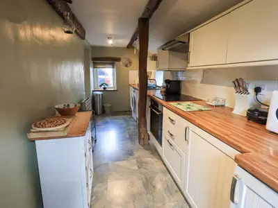 a kitchen with white cabinets and a wooden counter top at Jacky Garth Cottage in Keswick