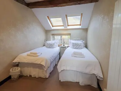 two twin beds in a room with a window at Jacky Garth Cottage in Keswick