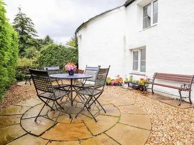 a patio with a table and chairs and a bench at Jacky Garth Cottage in Keswick
