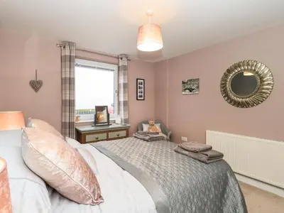 a bedroom with a bed and a mirror and a window at Solway View in Wigton