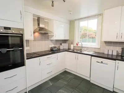 a kitchen with white cabinets and black counter tops at Hazelmere in Keswick