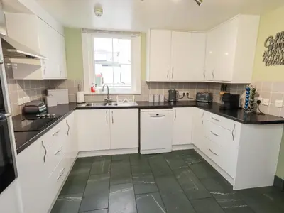 a kitchen with white cabinets and a green tile floor at Hazelmere in Keswick