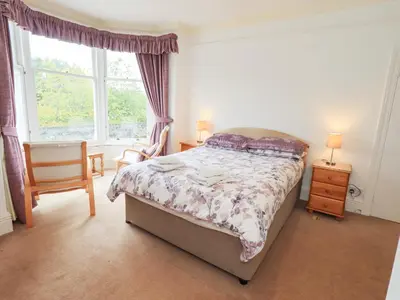 a bedroom with a bed and a chair and a window at Hazelmere in Keswick