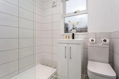 a white bathroom with a toilet and a window at Wellington View - Donnini Apartments in Ayr