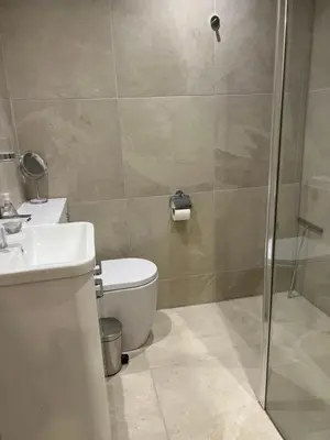 a bathroom with a shower and a toilet and a sink at Keswick Ground floor apartment with parking in Keswick