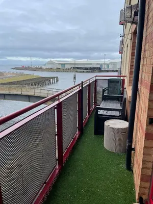 a balcony with a bench next to the water at The Marine - Balcony - Beach View - Coorie Doon Stays in Ayr