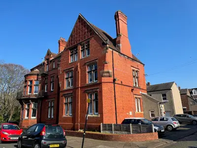 a red brick building with cars parked in front of it at Red Gables - Ground Floor in Carlisle