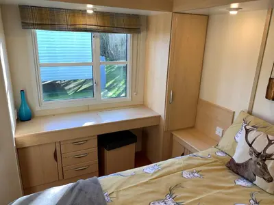 a bedroom with a bed and a desk and a window at Holiday Caravan - Sleeps 4 with Parking in Whithorn