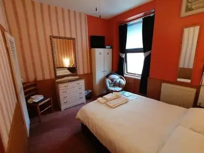 a bedroom with a bed and a dresser and a mirror at All Seasons Guesthouse in Douglas