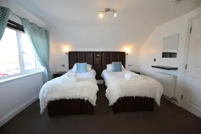 a bedroom with two beds with white and blue pillows at The Inn on the Loch in Castle Douglas